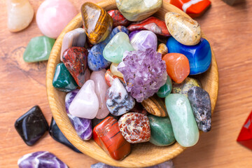 A cup with natural multi-colored minerals and individual minerals on the background of a wooden table. Mineralogy, isotherics