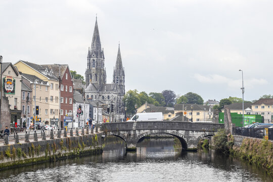 View of the River Lee reflects the stone bridge and the spires of St. Fin Barre's Cathedral under a cloudy sky, Cork, County Cork, Ireland.