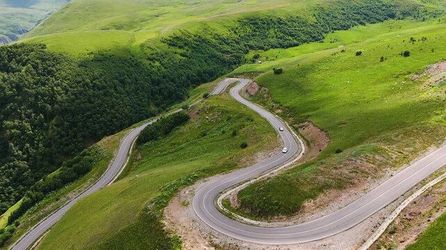 The car is driving along a winding serpentine road in the Caucasus Mountains to the Dzhila Valley.