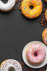 Stack of glazed colorful assorted donuts with sprinkles on black background.