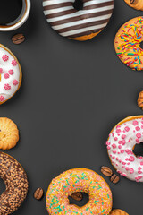 Stack of glazed colorful assorted donuts with sprinkles on black background.