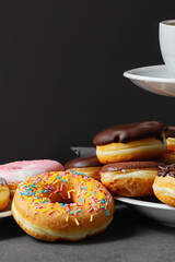 Stack of glazed colorful assorted donuts with sprinkles on black background.