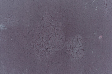Abstract dark purple cracked paint texture on old wall surface showing decay and weathering detail.