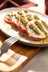 Italian caprese salad with tomatoes and mozarella. Pesto sauce and olive oil.