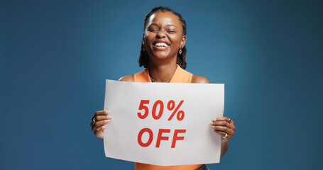 Happy, black woman or discount with billboard sign for advertising on a blue studio background. Female person, promoter or African model with poster, half price or marketing offer for shopping deal