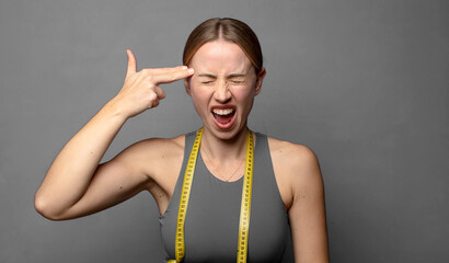 looking unhappy and stressed, suicide gesture making gun sign with hand, pointing to head. fitness concept