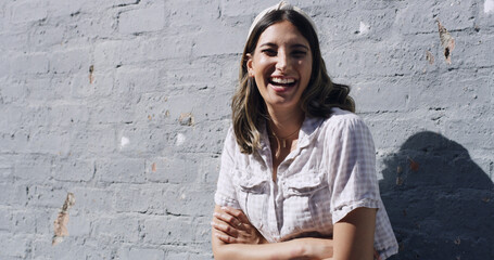 Brick wall, portrait and woman laughing with arms crossed, university student and study break...