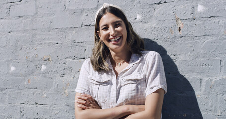 Portrait, wall and happy woman in city, arms crossed and fashion with confidence, holiday and calm. Funny, outdoor and person with pride, stylish clothes and casual outfit with vacation and trendy