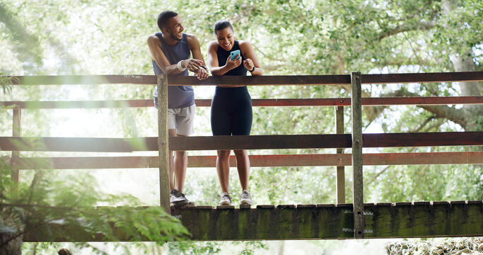 Bridge, below and couple with smartphone, fitness or bonding together with social media. Funny meme, outdoor or man in park, healthy woman or cellphone with training, connection or low angle with app