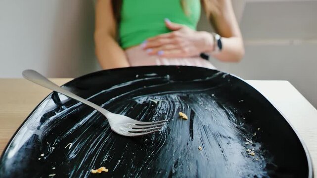 Slow motion shot zooming in on dirty plate with woman in discomfort