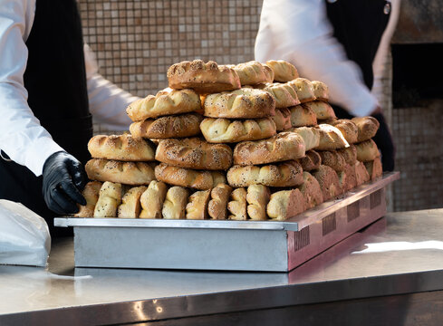 Men in gloves carrying a pile of traditional uzbek nan bread with sesame on tray. Not AI