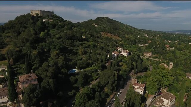 Aerial view of Rocca d'Asolo, standing prominently atop a hill, surrounded by lush greenery and scattered houses, Asolo, Veneto, Italy.