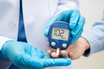 Asian doctor using digital glucose meter for check sample blood sugar level to treatment diabetes.