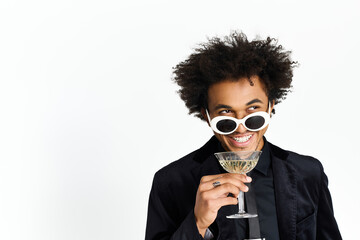 Charming young man enjoys a cocktail in stylish attire, capturing a moment of joy