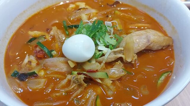 Red Seafood Jjampong, Red Spicy Seafood Korean Noodle Soup with Vegetable, shrimp, squid, and Clam on Bowl. 
