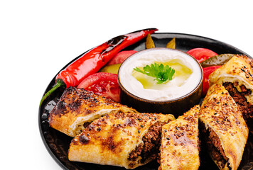 Delicious pastrama rolls served with yogurt and fresh vegetables on a plate