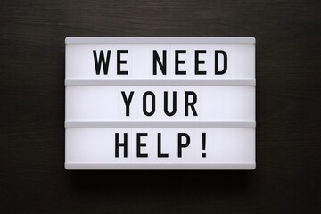 Illuminated Lightbox Displaying Message of Urgent Assistance Needed on Dark Background