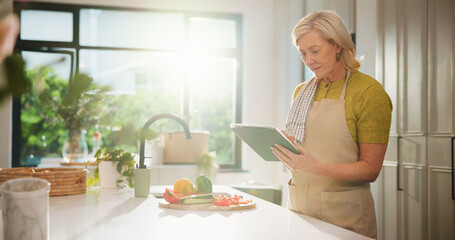 Senior woman, tablet and cooking in kitchen for search, recipe and online course with flare at...