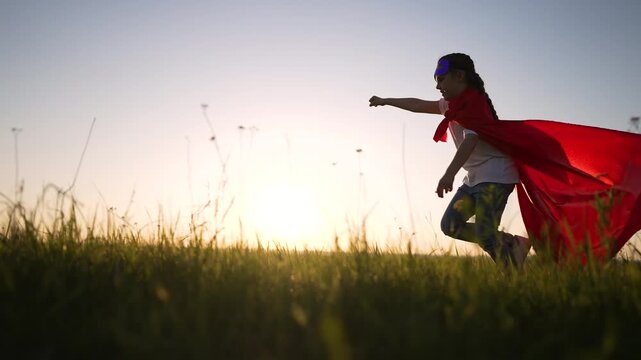 Child running with red cape forward through tall grass in sunlit field at sunset, play and imagination visible as superhero pose and cape flutter during joyful run under golden sun play imagination