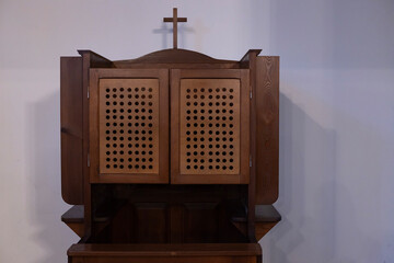 Traditional wooden confessional with lattice doors located in a serene church setting
