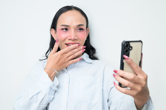 Portrait of a young Thai transgender person using phone against white background