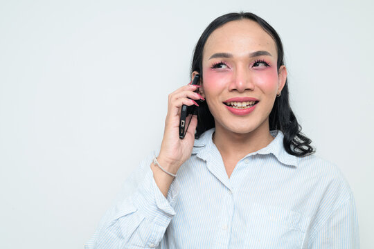 Portrait of a young Thai transgender person on the phone against white background