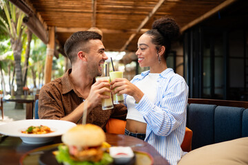 Multiethnic couple enjoying a joyful dining experience by the beach. Great food, perfect summer vibe