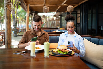 Young couple sharing dining experience at tropical restaurant, engaging with their online followers