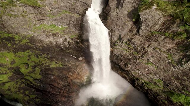 Aerial view of a powerful waterfall plunging down rugged, textured rocks, with green vegetation clinging to the cliffside, Manafossen, Dirdal, Rogaland, Norway.