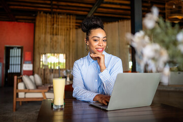 Happy freelancer enjoying a nutritious breakfast of smoothie and salad while working on a laptop
