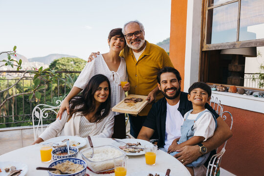 Happy family enjoying a Brazilian churrasco on a sunny outdoor patio