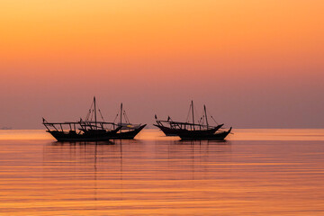 Doha, Qatar - October 24, 2025: Traditional fishing Dhow boat sailing at sea with sunrise...