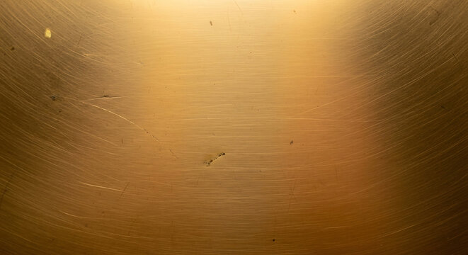 Textured brushed metal surface with warm golden hues