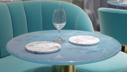 Round turquoise table with marble placemats and wine glass.