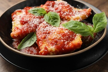 Delicious ravioli with tomato sauce, cheese and basil on table, closeup