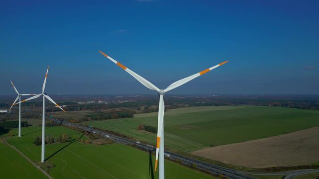 Wind farm turbines near highway clean energy. Smooth aerial view flight rone