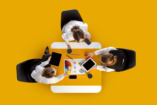 Team reviewing colorful charts and touching digital devices during discussion. Concept of marketing workflow, business training, HR communication and project teamwork.