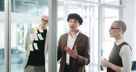 Conversation, glass wall and planning with business people in office together for project management. Collaboration, brainstorming and sticky notes with corporate employee team at work for meeting