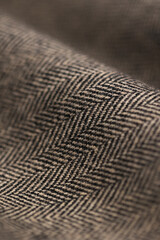 Close-up of lightweight English Herringbone tweed fabric. High-quality wool textile featuring the classic zigzag weave in warm, earthy tones. Perfect macro detail for sophisticated outerwear.
