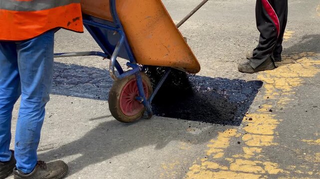 The footage emphasizes the labor and equipment involved in small-scale infrastructure potholes repair.