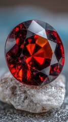 A close up macro photograph of a brilliant red faceted garnet gemstone.