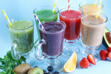 Different tasty smoothies in glasses and ingredients on light blue background, closeup