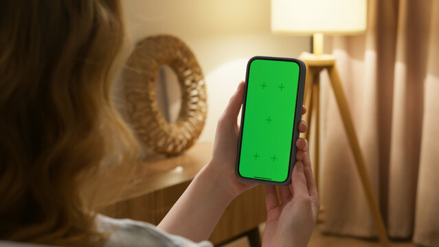 Woman use digital tech cell phone green screen mock up talk video call. Hand swipe click phone web site middle center. Girl hold mobile. Chroma key page. Cozy home background. Online app copy space. - Powered by Adobe