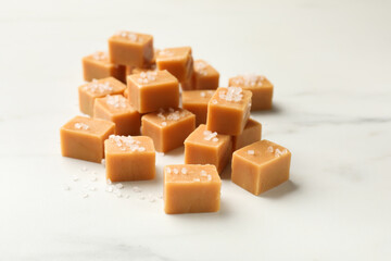 Tasty caramel candies with salt on light table, closeup