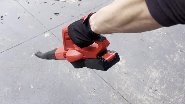 Handheld leaf blower in action: efficient outdoor cleanup on concrete surface.