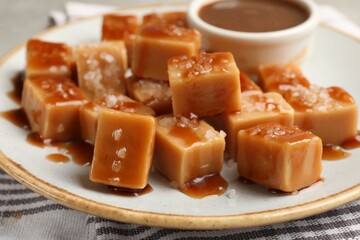 Tasty candies with salt and caramel sauce on table, closeup