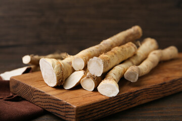 Fresh raw horseradish roots on wooden table, closeup