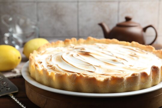 Tasty lemon meringue tart, server and fruits on wooden table, closeup. Space for text - Powered by Adobe