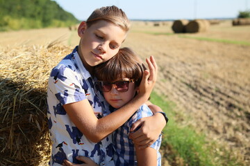 children huging each other in a wheat field