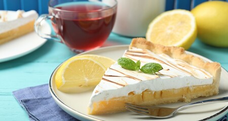 Slice of tasty lemon meringue tart with mint served on blue table, closeup